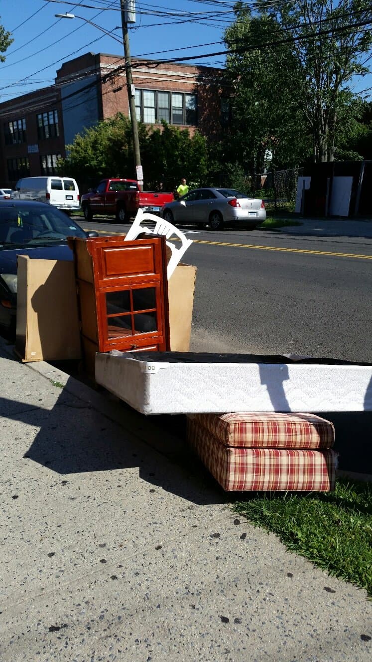 Furniture and household items staged for junk removal on a Stamford, CT street