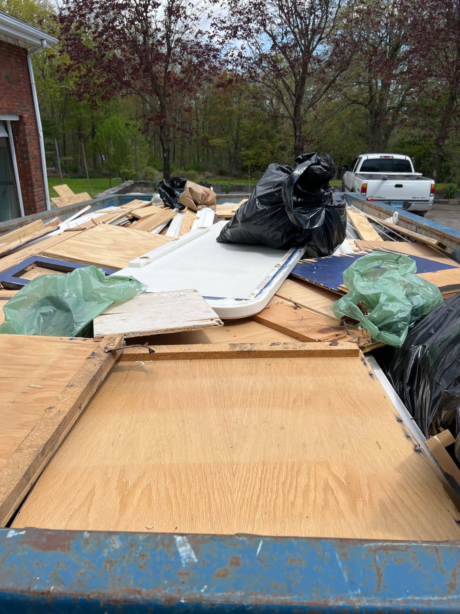 Roll-off dumpster loaded with plywood and renovation debris