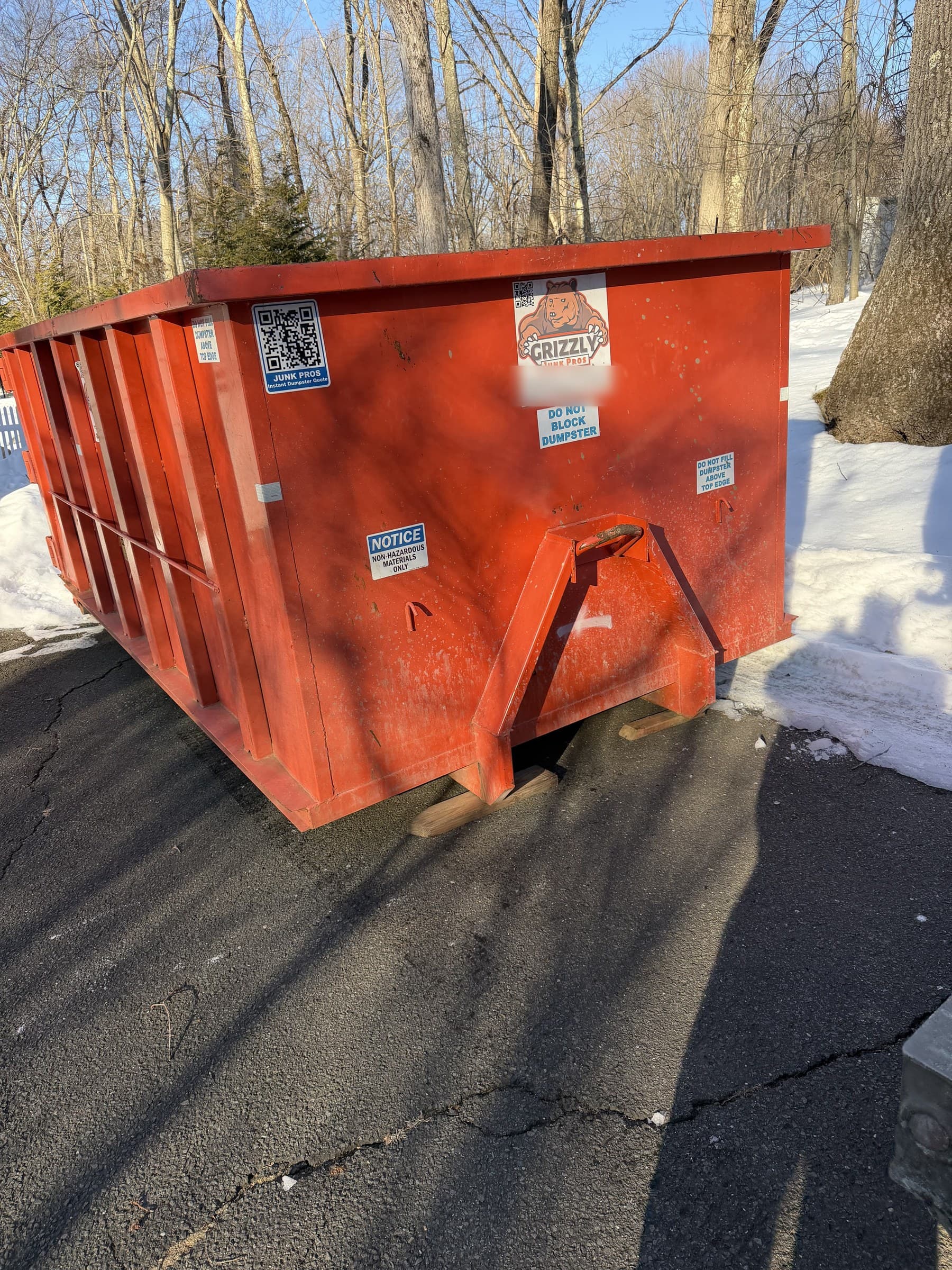 orange dumpster container by Grizzly Junk Pros