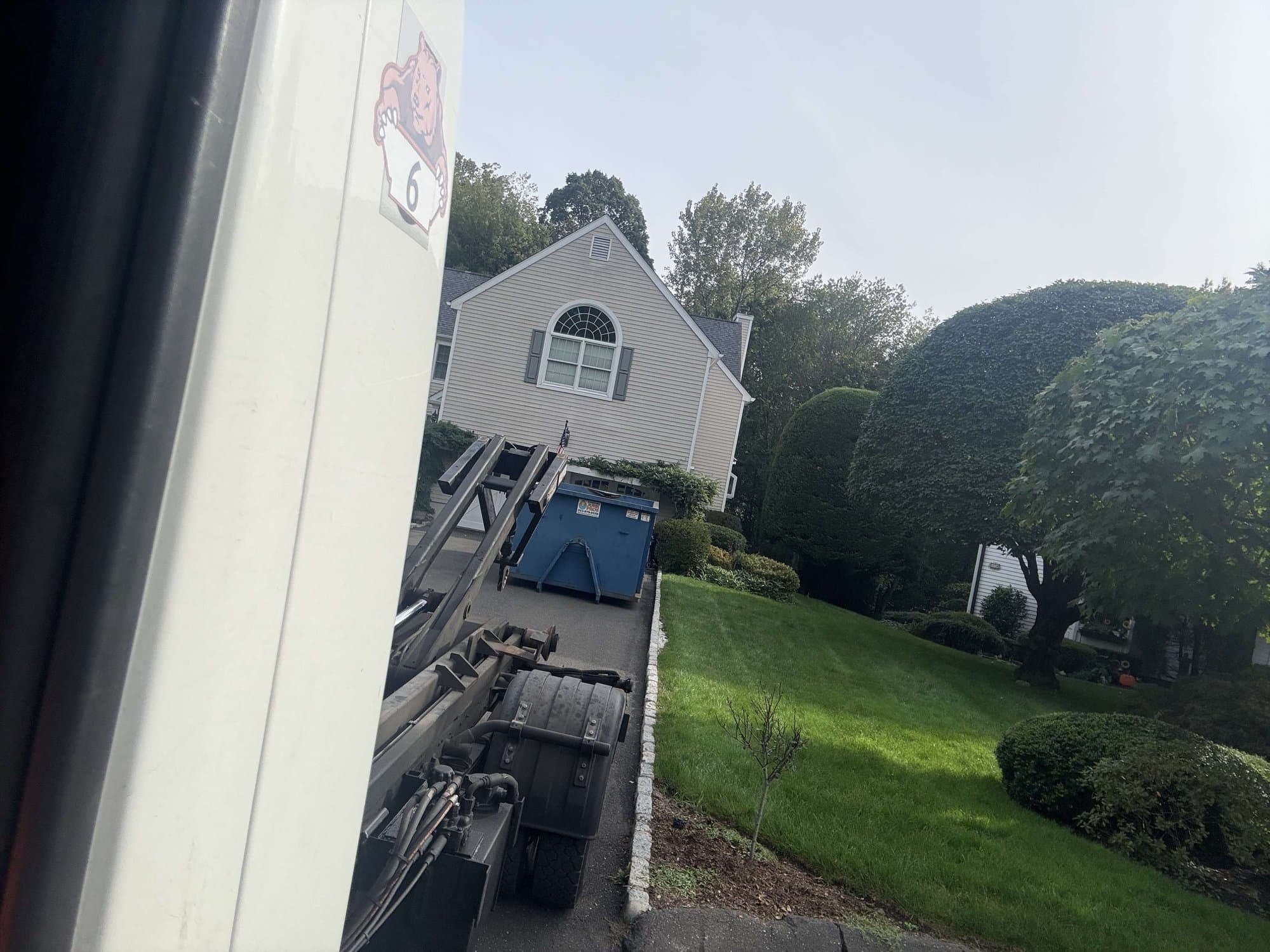 Grizzly Junk Pros dumpster being positioned at a residential CT property for a move-out cleanout